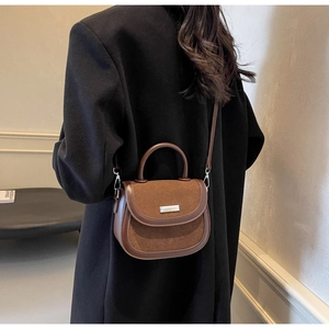 Détail d'un sac besace marron vintage alliant daim mat et textures de cuir lisse
