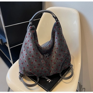 Detail of grey polka dot tote bag with red dots and white embroidered bow on a chair