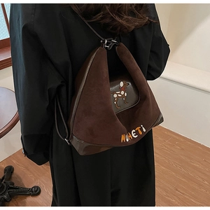 Dettaglio dello zaino in pelle scamosciata marrone con ricamo di cucciolo e pelle