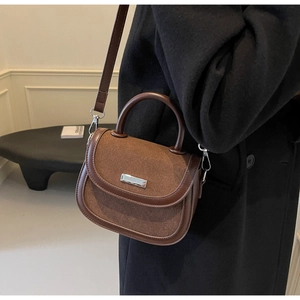 Détail d'un sac besace marron en daim avec boucle métallique et bandoulière
