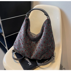 Detail of silver bow hardware on grey and red polka dot fabric shoulder bag