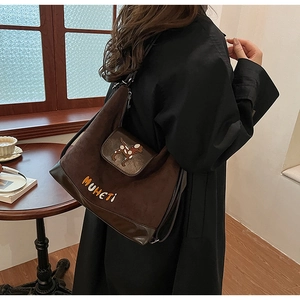Dettaglio borsa a tracolla marrone opaco con patch cane e piccola tasca zip
