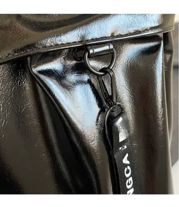 Macro detail of glossy black tote bag featuring metal hook and lettered shoulder strap