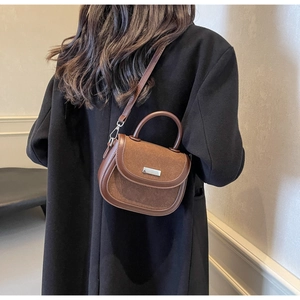 Gros plan d'un sac besace en cuir marron avec boucle argentée porté à l'épaule