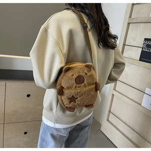 Detail of cute brown plush capybara crossbody bag with star embroidery and strap