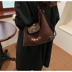 Dettaglio della borsa a secchiello in pelle scamosciata marrone con patch di cane