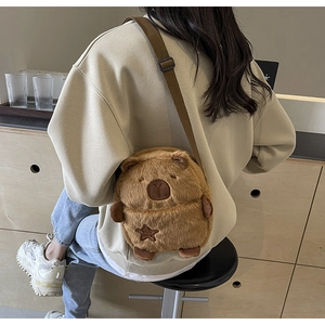 Detailed view of the fuzzy brown Capybara plush crossbody bag on a beige sweatshirt