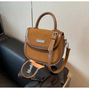 Détail d'un sac besace marron en bi-matière avec plaque logo métallique et bandoulière