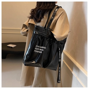 Glossy black tote bag with white typography and lettered ribbon strap detail