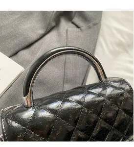 Détail du sac à main en cuir matelassé noir avec poignée ronde en métal argenté et cuir