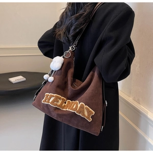 Dettaglio di una borsa tote in pelle scamosciata marrone con ricamo HELDAY e ciondolo