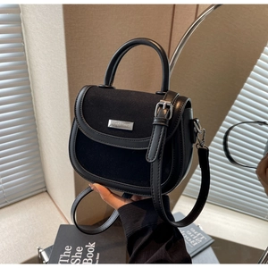 Détail montrant la texture du cuir et la plaque logo en métal du sac besace
