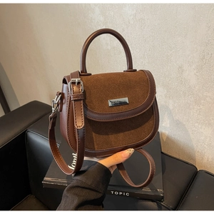 Détails du sac selle marron foncé avec coutures en cuir texturé et poignée ronde