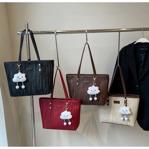Détail de quatre sacs cabas plissés en noir, bordeaux, marron et beige avec charms nuage