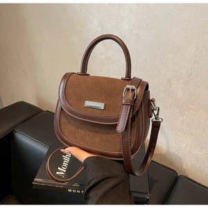 Gros plan d'un sac besace en cuir marron foncé avec logo argenté et poignée chic