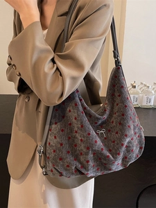 Polka dot gray corduroy tote bag with silver bow detail, worn with a beige outfit