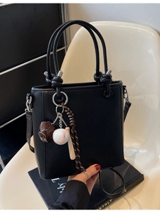 Minimalist black bucket bag with circular handle, sports charm and adjustable strap
