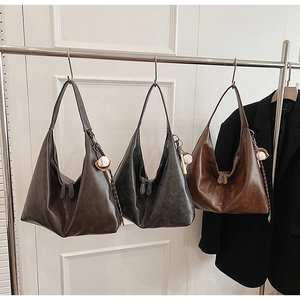 Detail view of large leather hobo bags in grey, black, and tan with baseball charms