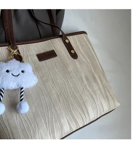 Détail du sac cabas crème avec texture ondulée et pendentif nuage moelleux