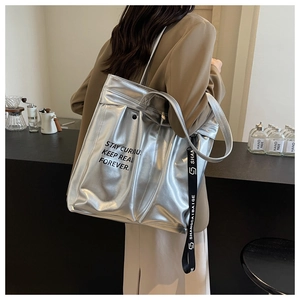 Detail of silver metallic tote bag with black strap in a minimalist cafe setting