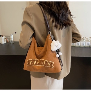 Dettaglio della borsa tote in pelle scamosciata marrone con ricamo HELIDAY e ciondolo nuvola