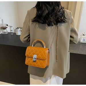 Détail du sac matelassé caramel avec poignée en métal argenté et fermoir à tourniquet