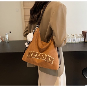 Dettaglio di grande borsa tote in pelle scamosciata marrone con scritta Holiday 3D e peluche