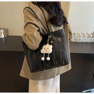 Détail d'un sac cabas noir texturé avec un charmant pendentif nuage en peluche blanc