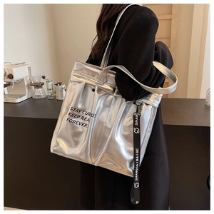 Detail showing the silver metallic tote bag with black slogan and hanging logo tag