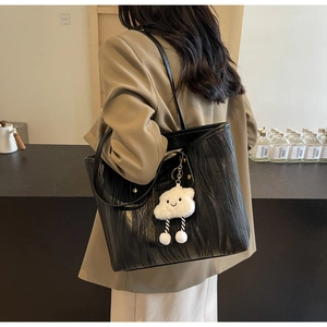 Détail du sac cabas noir avec texture ondulée verticale et accessoire nuage pelucheux
