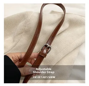Detail of adjustable brown leather shoulder strap with silver metal buckle and stitching