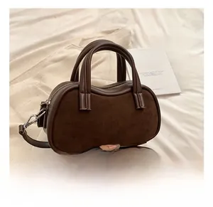 Close-up of brown suede and smooth leather stitching detail on vintage style handbag