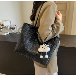 Gros plan sur un sac cabas noir texturé bois avec un charme nuage blanc dans un café