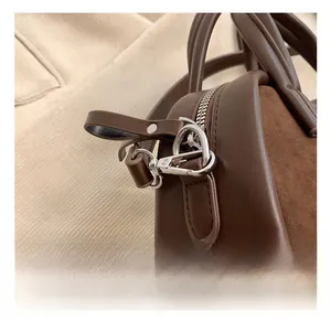 Detail of dark brown suede stitching and silver metal hardware on a vintage pillow bag