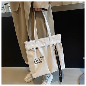 Detail of white glossy tote bag featuring Stay Curious print and black decorative lanyard