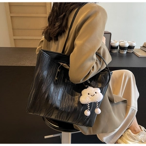 Détail d'un grand sac cabas noir à texture ondulée et breloque nuage blanc