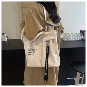 Detail of white glossy tote bag with stylish slogan and decorative ribbon strap