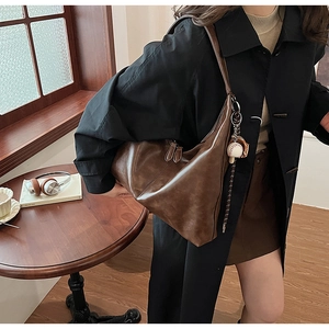 Close-up of brown soft leather tote bag with a baseball charm on a fashion model