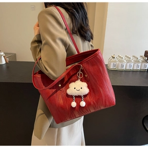 Détail du cabas rouge avec texture grain de bois et accessoire charm nuage en peluche