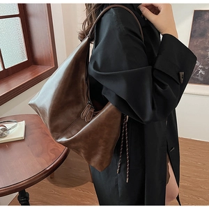 Detailed view of brown faux leather hobo bag texture with dual zippers and long strap