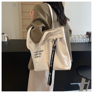 Detail of off-white tote bag featuring black text print and logo strap detail