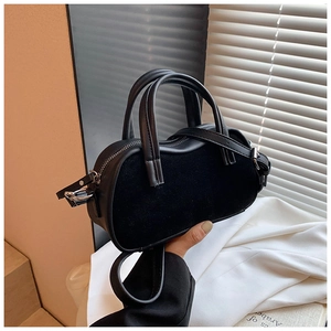 Detail of black suede and faux leather handbag with wave silhouette and metal zipper