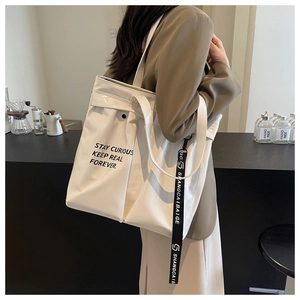 Detail of cream large capacity tote bag with black lettering and side strap for daily commute