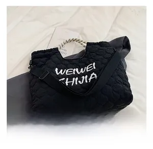Detail of black quilted tote bag featuring wave stitching and woven rope top handles