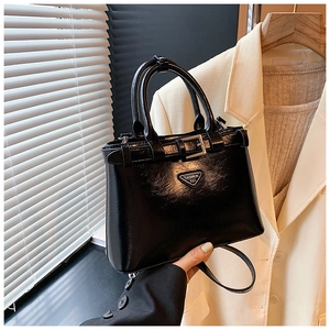 Détail du sac à main en cuir verni noir avec logo triangulaire et sangles à boucles