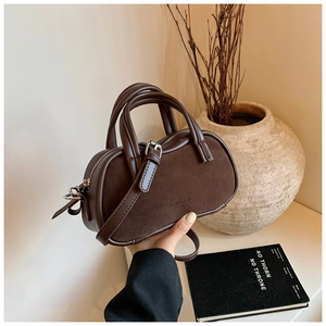 Close-up of a brown textured leather handbag featuring fashion embossed text and twin handles