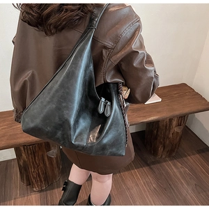 Detail of a large black hobo shoulder bag showing matte faux leather texture and zipper