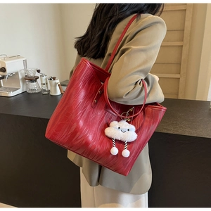 Détail du sac cabas rouge en cuir texturé avec motifs ondulés et charm nuage doux