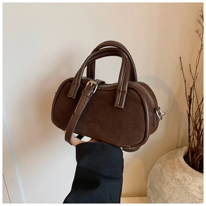 Close-up of retro brown suede boston bag with embossed leather detail and top handles