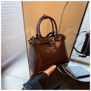 Détail du sac en cuir brillant marron foncé avec logo métallique et poignée supérieure